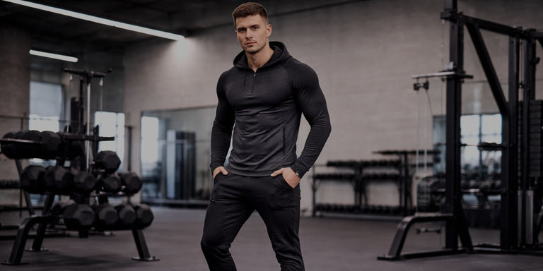 Man in a gym wearing a black hoodie and pants